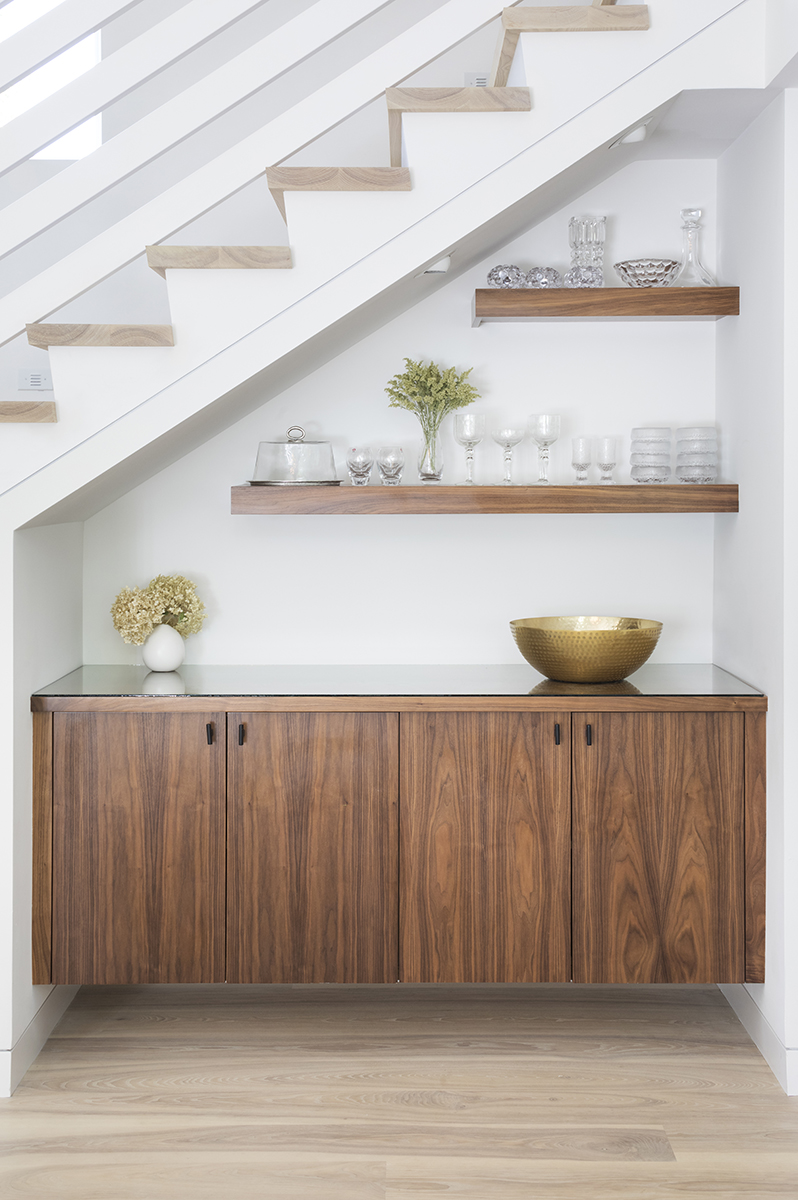 This custom built-in buffet creatively uses the space under the staircase as a focal point to the dining room area. AMEK