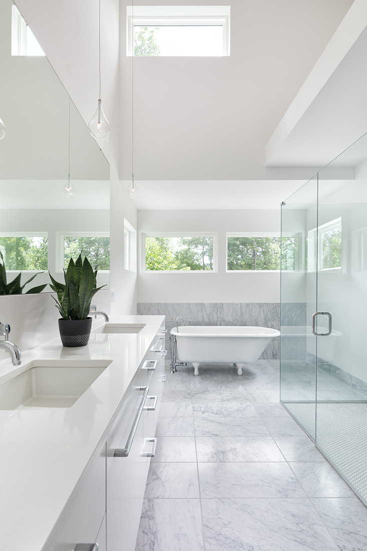 A vintage free-standing soaking tub is the centerpiece for this bright master bathroom. AMEK
