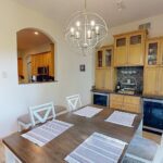 The original, traditional dining room featuring a built-in bar with golden oak cabinets and a small arched pass-through window looking into the kitchen, a before photo of a kitchen remodel in Inver Grove Heights, MN.