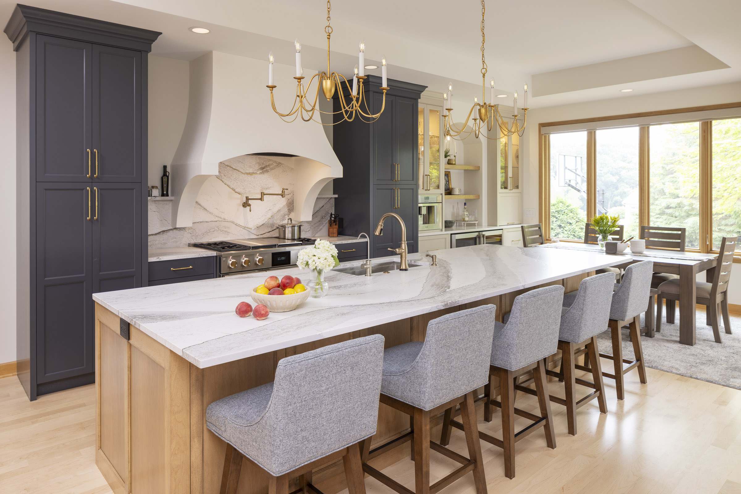 AMEK Inver Grove Heights kitchen remodel with large island, custom plaster range hood, full-slab quartz backsplash, and beverage bar.