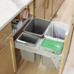 A smart and concealed kitchen waste center in Inver Grove Heights remodel, featuring a custom pull-out drawer with dedicated bins for trash, recycling, and compost, housed in a natural wood shaker cabinet, part of a kitchen remodel.