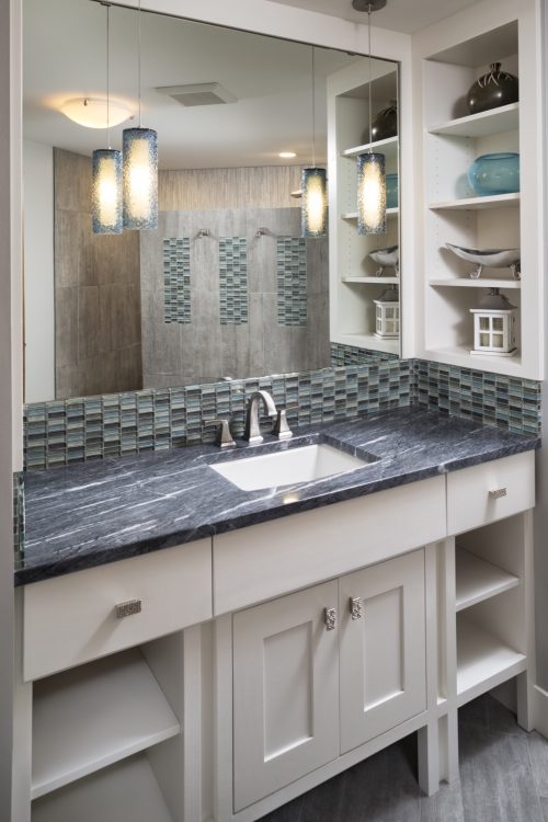 140630_AMEK_3820Pascolo_113s8tc Modern basement bathroom featuring a white shaker-style vanity with a dark countertop, a large mirror, and built-in shelving. Part of a basement remodel in Chaska, MN.
