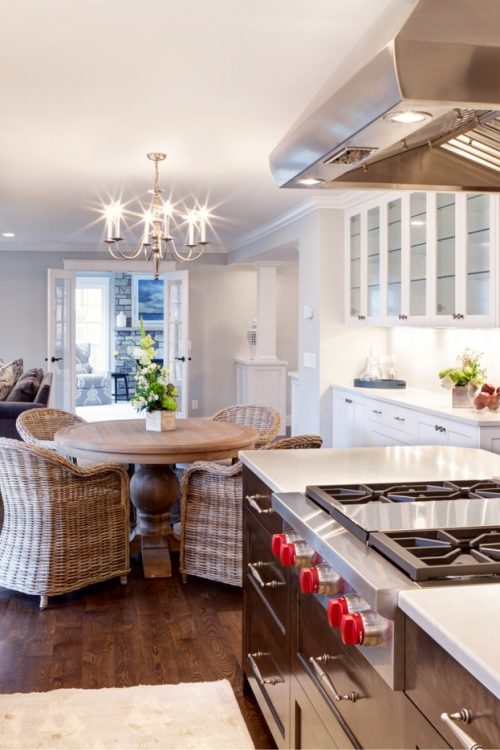 Gourmet kitchen with a large island featuring a gas cooktop, a professional stainless steel range hood, and white shaker cabinets, part of a whole home remodel in Wayzata, MN.