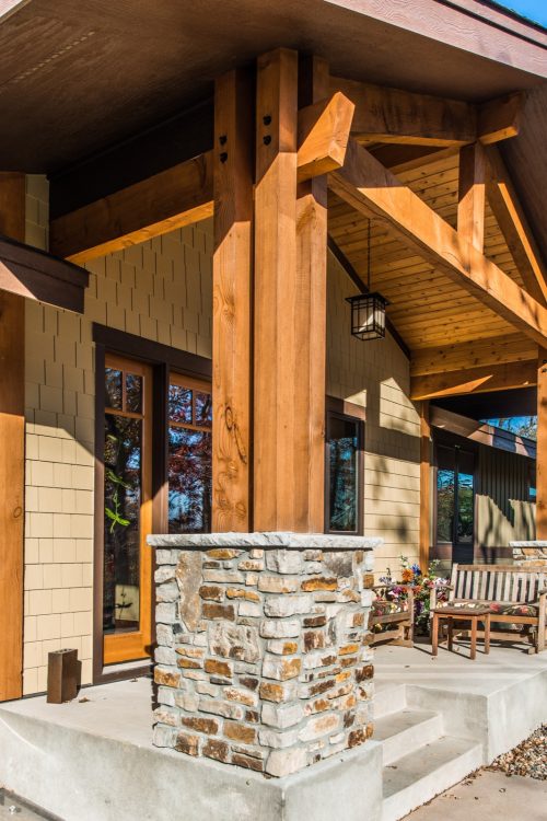 Covered front porch with heavy timber wood beams and stone support pillars, part of a new custom home in Mendota Heights, MN.